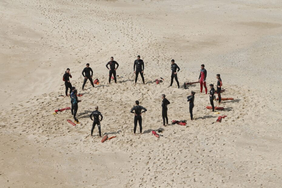 People in wet suits standing in a heart shape on a beach - heart signifies Values.