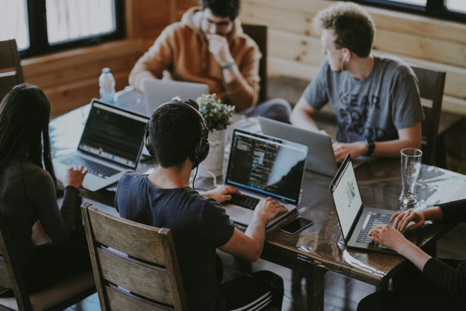 A group of young people on laptops collaborate together in the workplace.